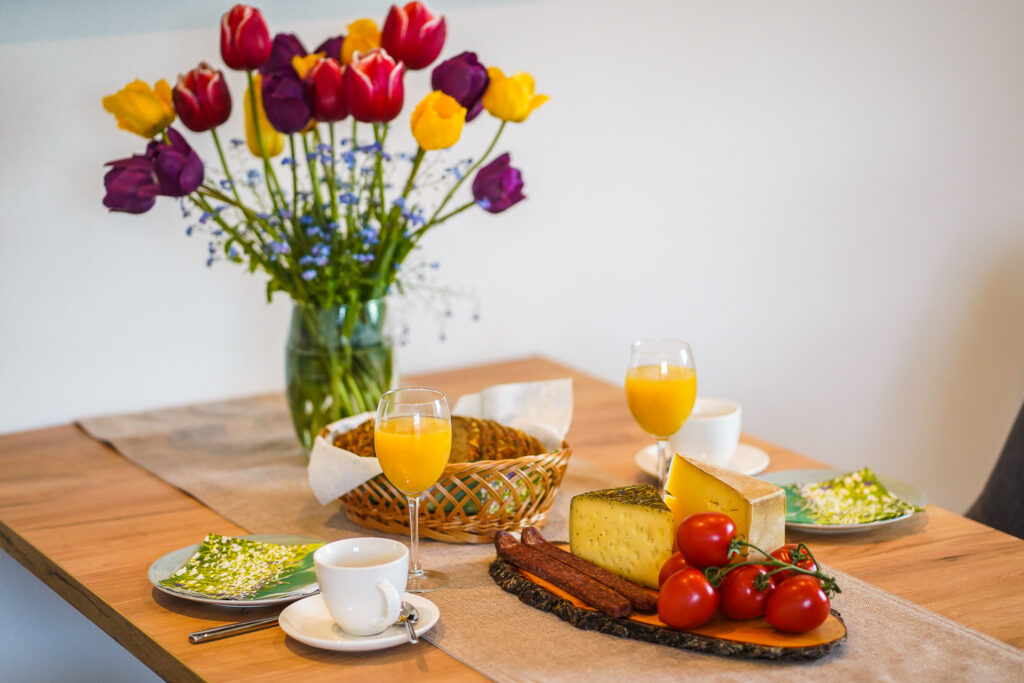 herzhafter Frühstückstisch mit Tulpenstrauß auf dem Tisch