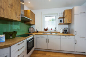 Wohnküche in Ess- und Wohnbereich mit Arbeitsplatte und Schränken aus Echtholz